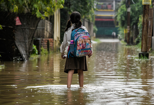 Guwahati, India. 25 May 2022.  A girl returns from school wades across a flooded street after heavy rains, in Guwahati. Waterlogging is a common scene in Guwahati city due to poor drainage system.