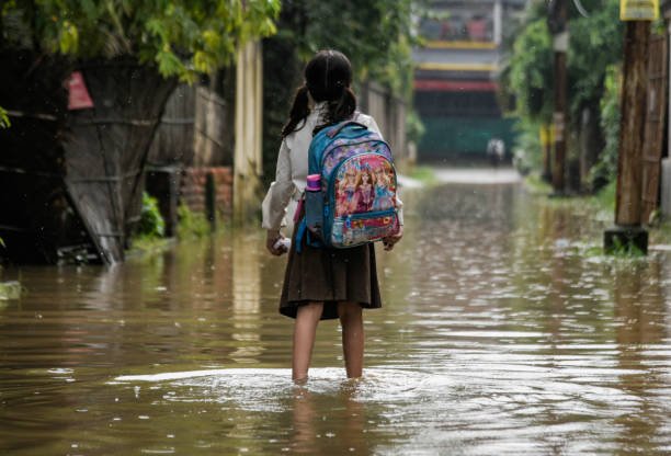 Waterlogging in India Guwahati, India. 25 May 2022. A girl returns from school wades across a flooded street after heavy rains, in Guwahati. Waterlogging is a common scene in Guwahati city due to poor drainage system. india cities in the rain stock pictures, royalty-free photos & images