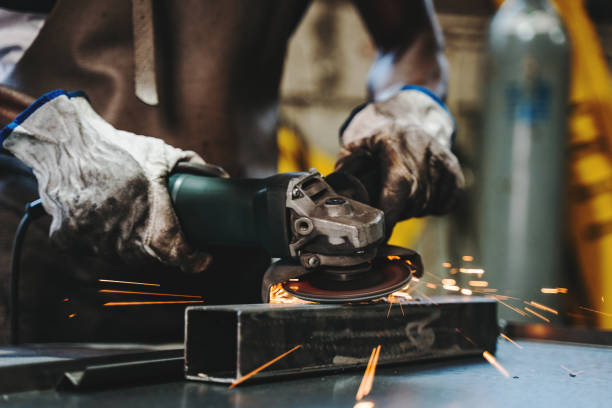 welder grinding peace of metal - protective glove machinist human hand african descent imagens e fotografias de stock