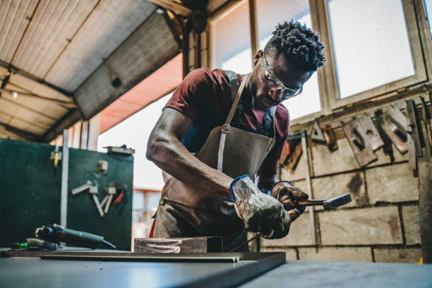 industrial welder working with hammer and chisel - protective glove machinist human hand african descent imagens e fotografias de stock