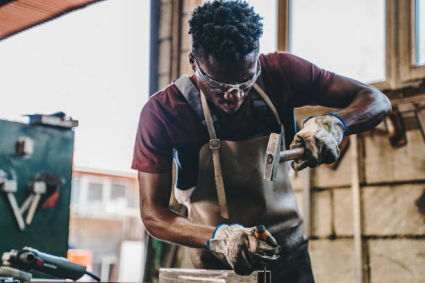 industrial welder working with hammer and chisel - protective glove machinist human hand african descent imagens e fotografias de stock