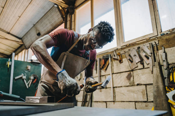 industrial welder working with hammer and chisel - protective glove machinist human hand african descent imagens e fotografias de stock