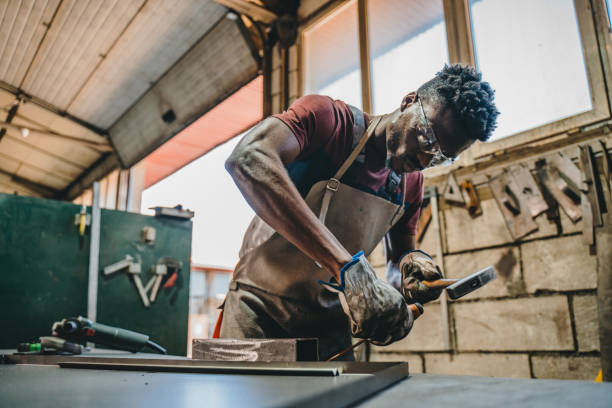 industrial welder working with hammer and chisel - protective glove machinist human hand african descent imagens e fotografias de stock