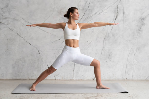 istock Young woman practicing yoga Warrior pose, Virabhadrasana against texturized wall 1399218179