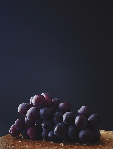 Ripe juicy dark grapes on wooden desk, food and wine, organic fruits concept
