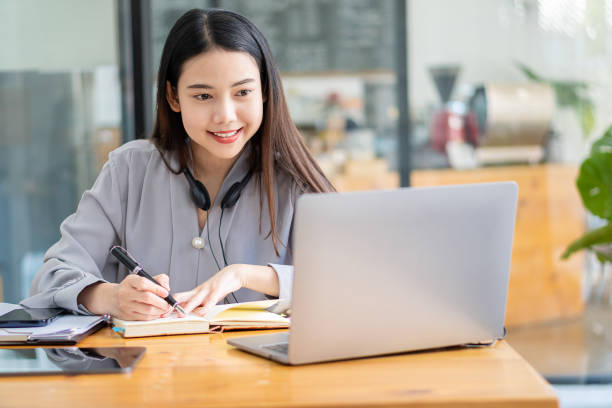 istock Asian students hang wireless headphones around their necks and write laptops to learn languages online. Watch and listen to laptop webinars. video call and e-learning ideas at home 1399220767