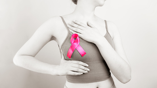 woman doing manual breast examination. pink ribbon as a symbol of World Breast Cancer Day. symbol of public conscious