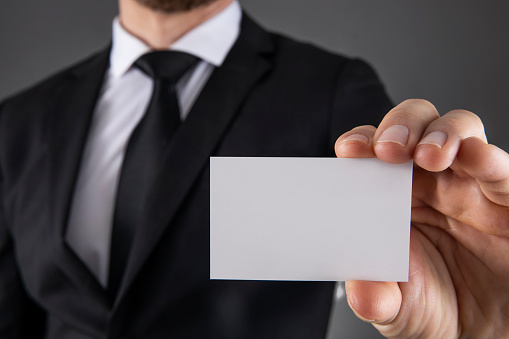 Businessman showing blank business card on gray background