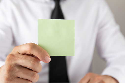 Businessman showing green blank adhesive note