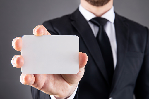 Businessman showing blank business card on gray background