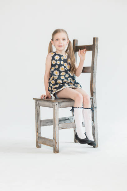 Happy little girl relaxing on chair at balcony and looking at camera.