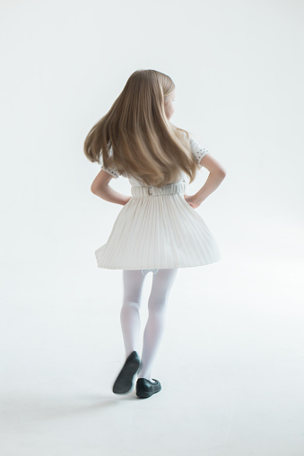 Girl in a white dress and in a white photo studio