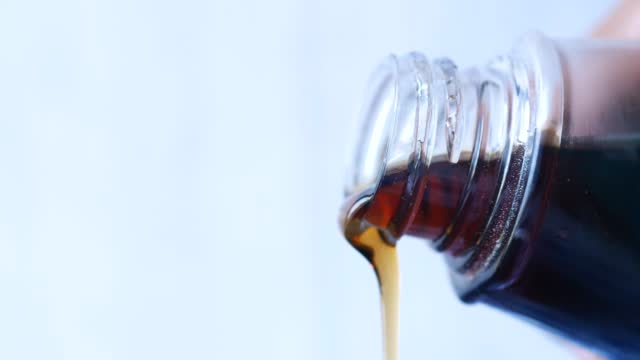 Bottle of maple syrup pouring close up