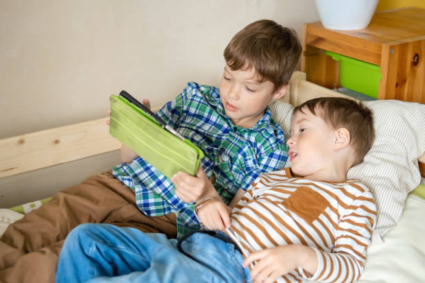 istock Two Caucasian boys are lying on bed with digital tablet, playing online games, using Internet, communicating on social networks. Children's dependence on gadgets. 1399229641