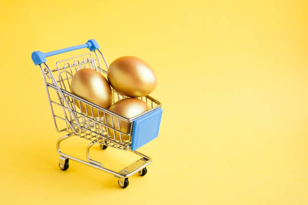 shopping cart with three golden eggs isolated on yellow background. easter sale banner. copy space - wealth eggs animal egg easter egg imagens e fotografias de stock