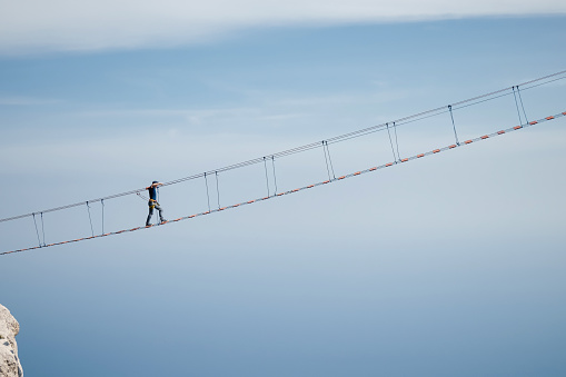 The young man risking life go on rope bridge on sky