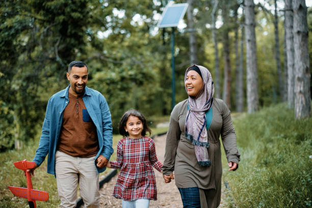 istock Happy Middle Eastern family holding hands while walking through the park. 1399233414