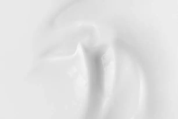 White hand or face cream texture in macro. Moisturizer, cleanser, coconut beauty product. Abstract background for cosmetics presentation.