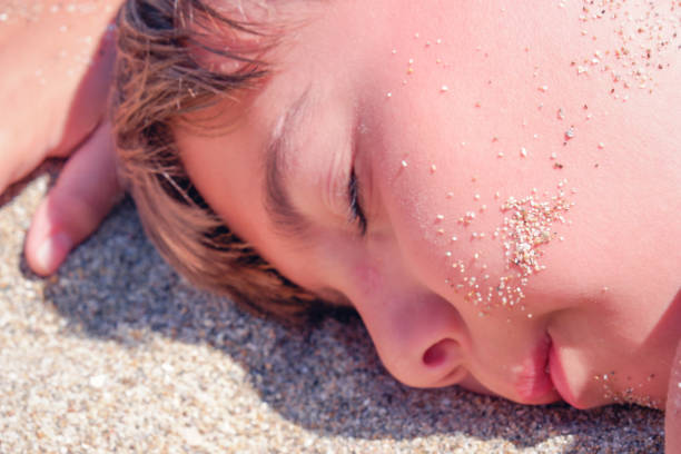 istock Portrait of boy with closed eyes lying on sand 1399237122