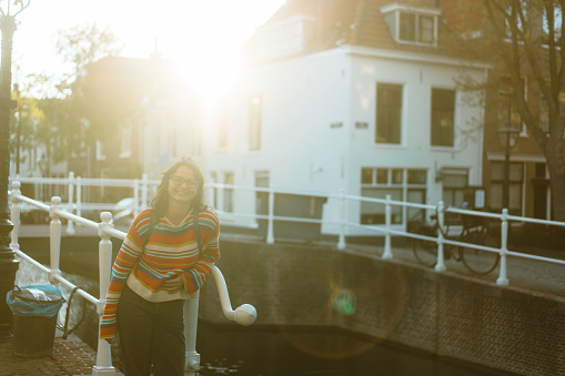 Young Caucasian woman in coat  walking in Leiden town at sunset