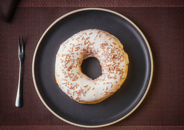 Tasty donut isolated on a plate on a fine table. Donuts, with white chocolate sprinkled with chocolate chips, Fine pastries