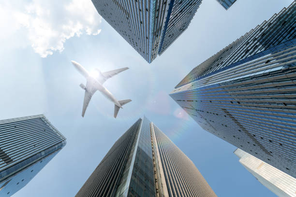 airplane fly over modern office buildings with sunshine, low angle view.