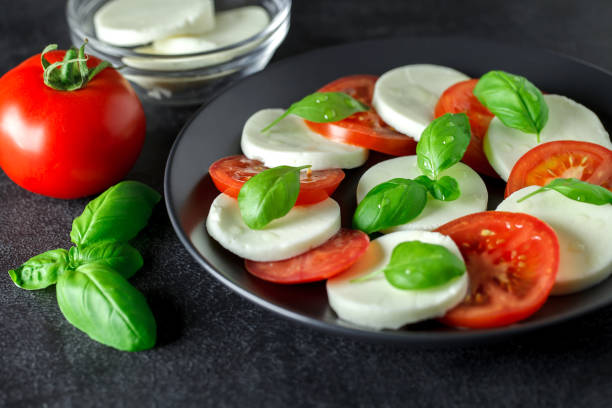 istock Caprese, Iitalian appetizer of mozzarella, tomatoes and basil, on dark background, selective focus. 1399248453