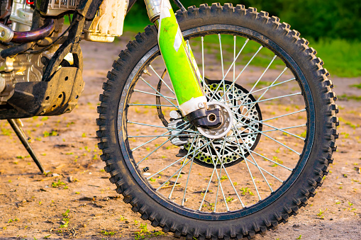 the front wheel of an extreme cross enduro motorcycle at sunset. off-road. close-up