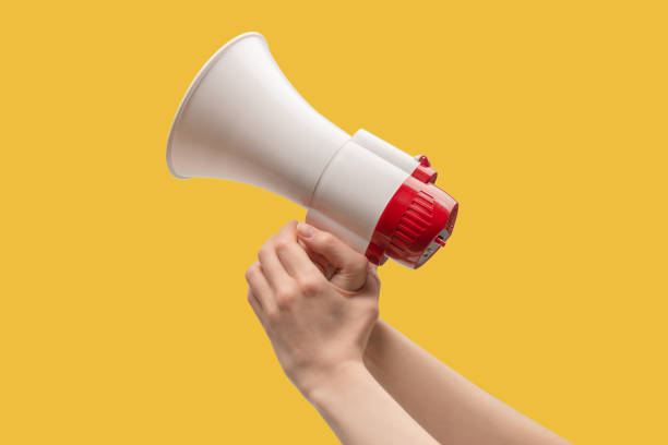 istock Megaphone in woman hands on a yellow background. 1399250013