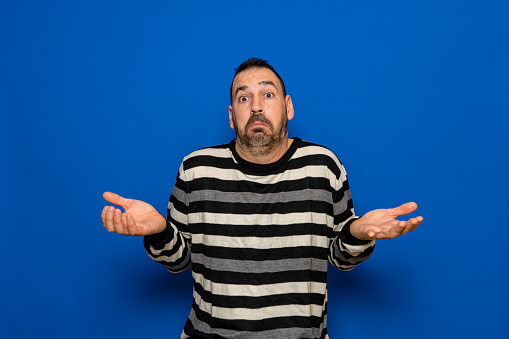 Latin man with beard doubt expression, concept of confusion and amazement, uncertain future isolated on blue background.