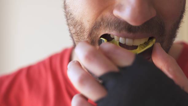 hombre joven que se pone protector bucal antes del entrenamiento de combate de boxeo - ropa protectora deportiva fotografías e imágenes de stock