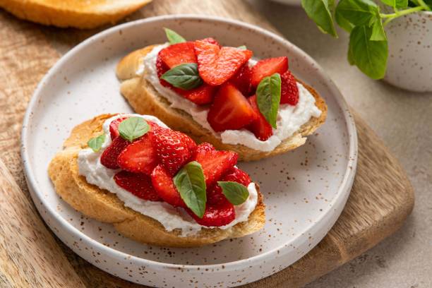istock Bruschetta with goat cheese or ricotta witn strawberry and basil. Appetizer with berries. Summer healthy breakfast. Selective focus. 1399252840