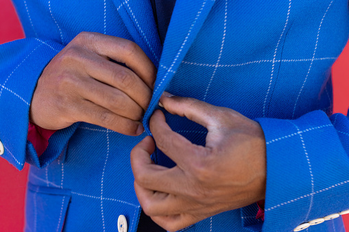 close up of man fastens his jacket. Groom getting ready. Businessman putting on his jacket. Black latin person