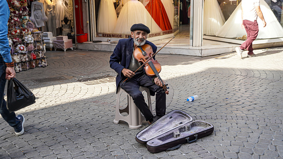 An old and homeless violinist plays his violin at the street and asks for alms in Konak, Izmir, Turkey on May 24, 2022