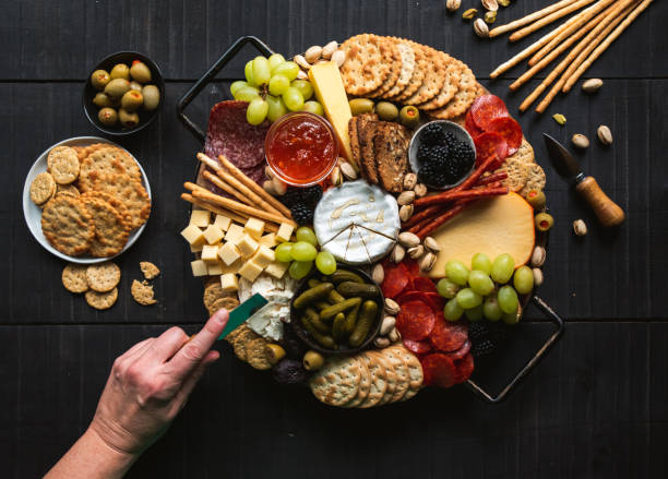 istock Hand over charcuterie board of meat, cheese, fruit, crackers. 1399264499