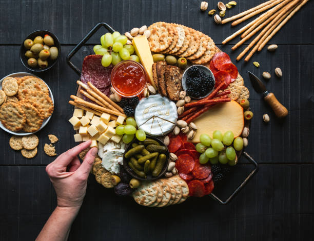 istock Hand over charcuterie board of meat, cheese, fruit, crackers. 1399264502