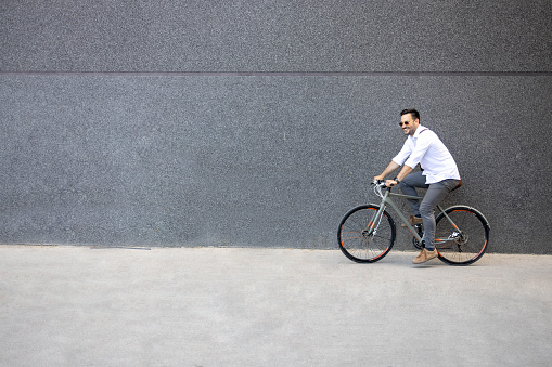 Business man riding a bike in front of black wall