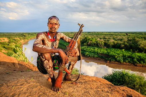 Young African man from Karo tribe posing with AK-47 / Kalashnikov - Ethiopia, East Africa.