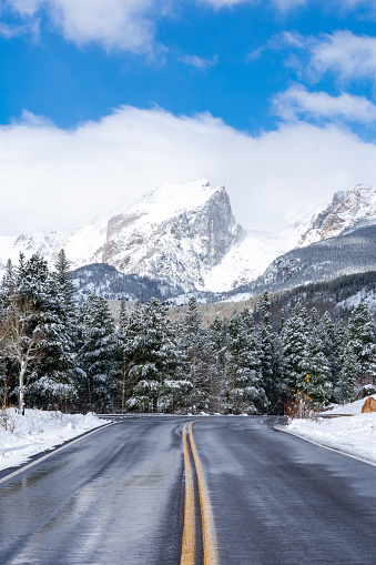 Open road with snow capped mountains and trees