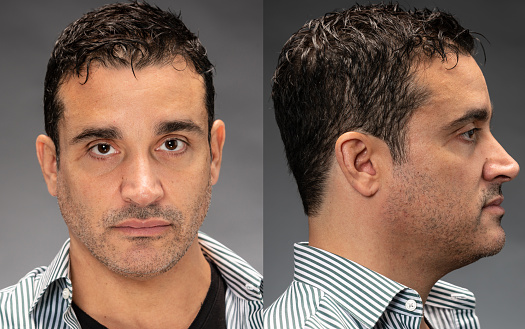 Serious man front and profile mugshots on gray background