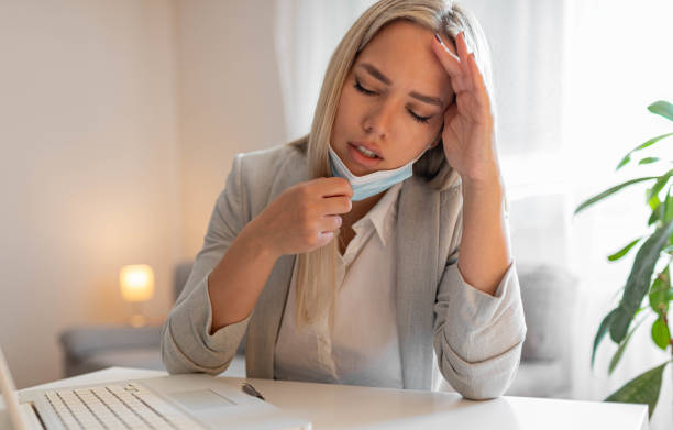 istock Woman working in the office and having difficulties breathing with face mask, she is pulling the mask down. The woman had to remove the mask to breathe after having to wear it for a long time 1399269088