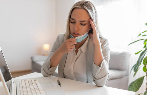 istock Woman working in the office and having difficulties breathing with face mask, she is pulling the mask down. The woman had to remove the mask to breathe after having to wear it for a long time 1399269093