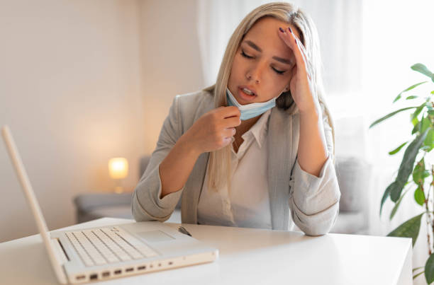istock Woman working in the office and having difficulties breathing with face mask, she is pulling the mask down. The woman had to remove the mask to breathe after having to wear it for a long time 1399269158