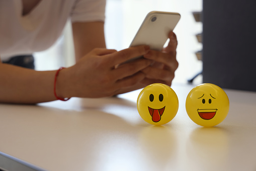 Woman holding mobile phone with smile emoji
