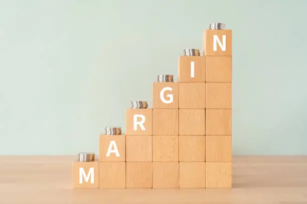 Wooden blocks with "MARGIN" text of concept and coins.