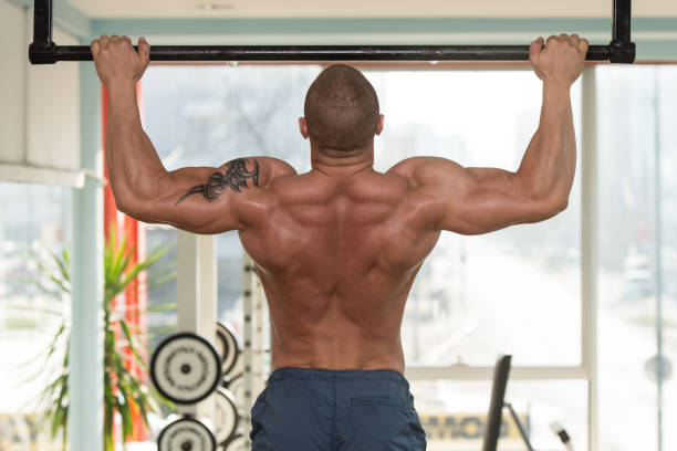 männliche athlet tun pull ups - body building men flexing muscles male stock-fotos und bilder