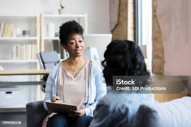 Mature Female Counselor Gives Unrecognizable Young Woman Advice Stock Photo - Download Image Now