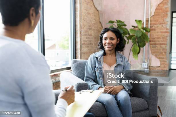 Young Woman Smiles While Answering Therapists Questions Stock Photo - Download Image Now