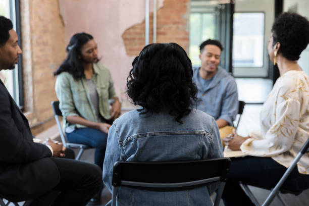 istock Members of therapy group interact with female counselor 1399285443