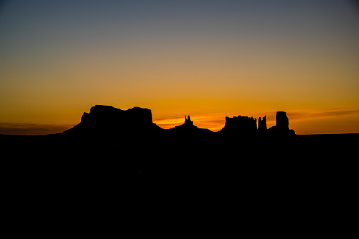 Sunrise behind Stagecoach, Bear and Rabbit, and Castle Rock formations in Monument Valley, Navajo Tribal Park, Utah.
